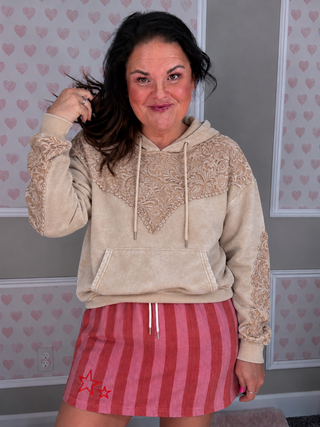 Sterling Kreek Tooled Frontier Hoodie in tan featuring intricate floral western tooled-inspired lace detailing across chest, shoulders and sleeves, drawstring hood, kangaroo pocket, and ribbed cuffs.