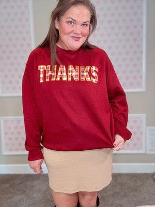 Burgundy long-sleeve pullover with plaid patch and embroidered edges — soft, stretchy fabric perfect for cozy fall outfits.