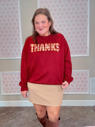 Burgundy long-sleeve pullover with plaid patch and embroidered edges — soft, stretchy fabric perfect for cozy fall outfits.