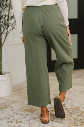 Person wearing green pants standing indoors with a blurred background
