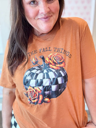 Person wearing an orange t-shirt with a Fall graphic design and text.