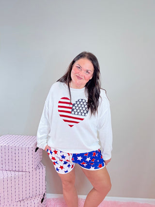 Patriotic Heart Flag Sweater – Mid-weight knit sweater with an American flag heart graphic, designed in an oversized fit for a trendy, casual look.
