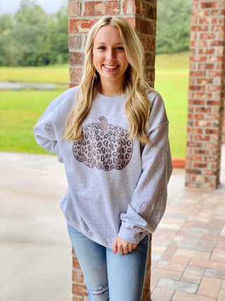 Woman wearing a gray sweatshirt with a leopard print design outdoors.