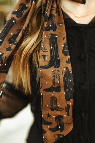 Brown satin bow with cowboy boot pattern worn by a person