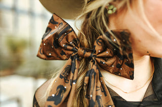 Close-up of a person wearing a patterned satin bow with a blurred background