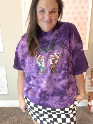 Person wearing a purple tie-dye t-shirt with graphic design indoors.