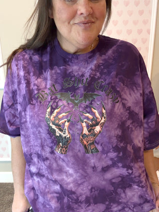 Person wearing a purple tie-dye t-shirt with graphic design and text.