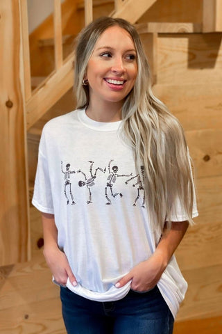 Woman wearing a white t-shirt with skeleton designs in a wooden interior setting