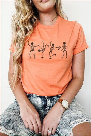 Person wearing an orange t-shirt with skeleton designs on a plain background