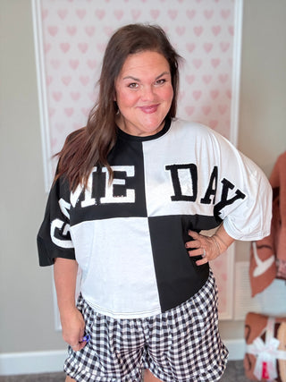 Front view of a black color block top with chenille football patches and sequin outline, styled with a mom crop fit – perfect for game day.