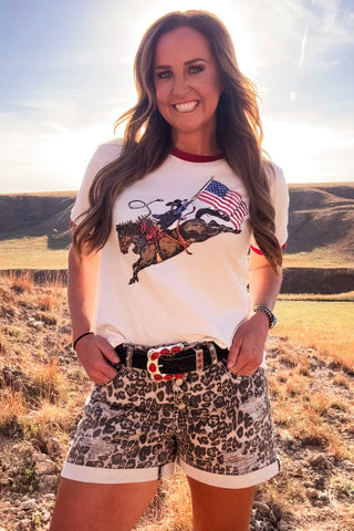 Woman wearing a graphic t-shirt and leopard print shorts in a desert landscape