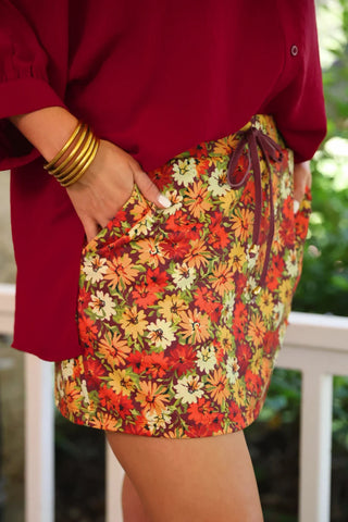 Women's floral fall skort featuring warm autumn blooms, built-in shorts, stretchy back waistband, adjustable drawstring, and functional side pockets. 