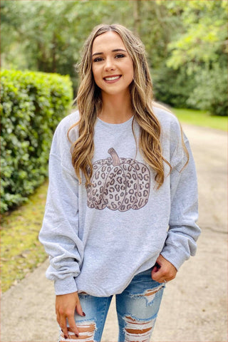Woman wearing a gray sweatshirt with a leopard print design outdoors.