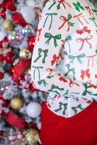 Woman wearing sheer black mesh top with festive bow print, mock neckline, and lettuce hems.