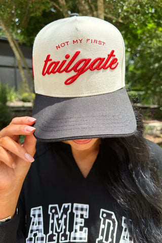 Cream and black game day hat with embroidered "Not My First Tailgate" lettering and embroidered bow detail.