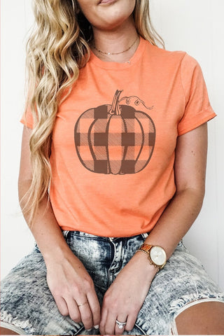 Person wearing an orange t-shirt with a black pumpkin graphic on a plain background