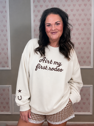Woman wearing a white sweatshirt with text and checkered shorts in a room with heart-patterned wallpaper.
