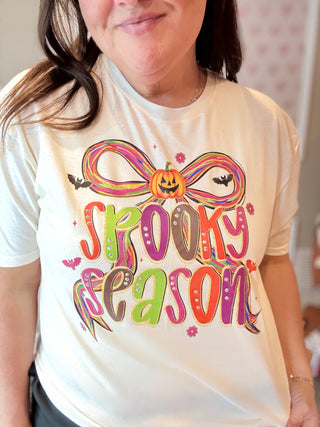 Person wearing a white t-shirt with 'Spooky Season' graphic design.