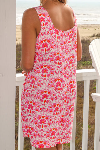 Person wearing a pink floral dress on a beach