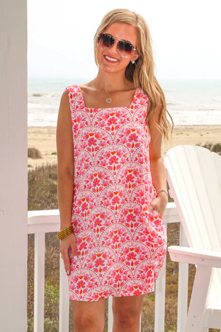 Woman wearing a pink floral dress on a beach setting
