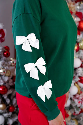Soft cotton-poly green pullover with bow sleeves, trendy holiday outfit inspo close-up.