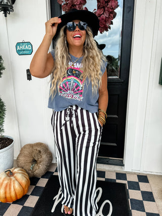 Woman wearing a graphic t-shirt and striped pants standing on a porch.