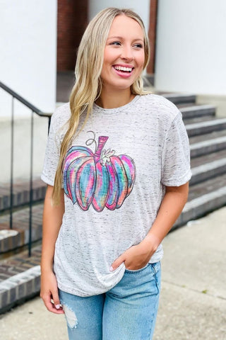 Woman wearing a gray t-shirt with a colorful pumpkin graphic outdoors.